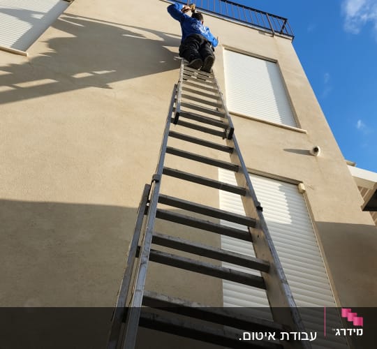 אדם על סולם גבוה ליד מעקה גג